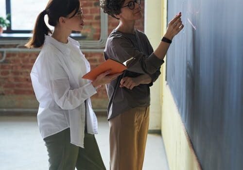 Two people are standing in front of a wall.